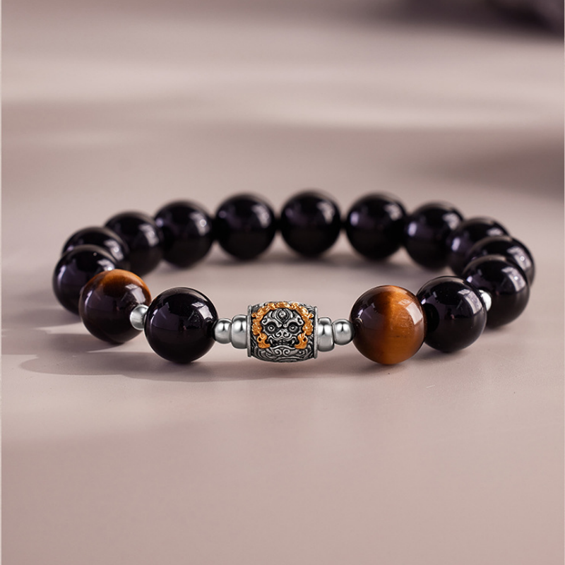 Obsidian and tiger eye Qilin bracelet on a taupe background