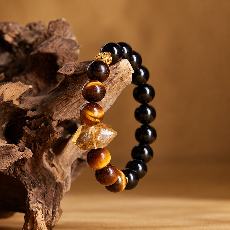 Obsidian bracelet draped over wood with golden brown tiger eye beads