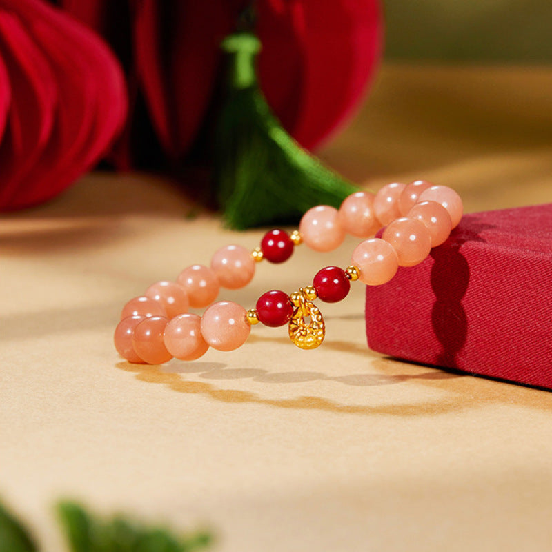 Orange moonstone and pressed cinnabar bracelet resting beside a red book