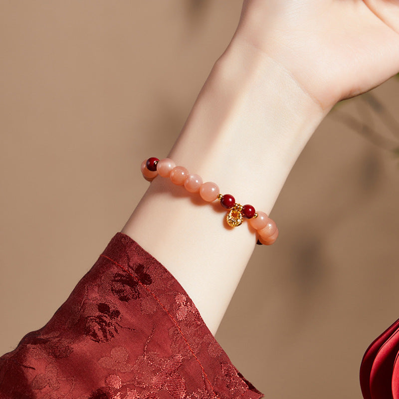 Close wrist view of orange moonstone bracelet and deep red cinnabar beads