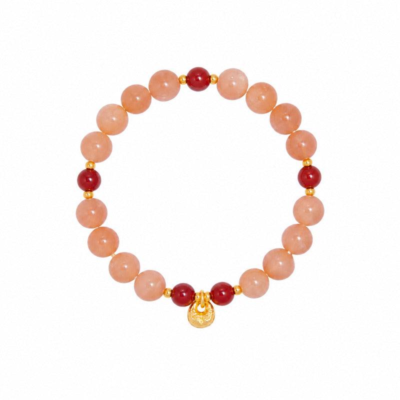 White background view of orange moonstone bracelet with fortune bag charm