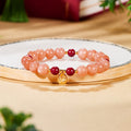 Orange moonstone fortune bag bracelet displayed on a softly lit round tray