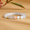 Peach blossom cat-eye glass bracelet resting on a warm ochre background