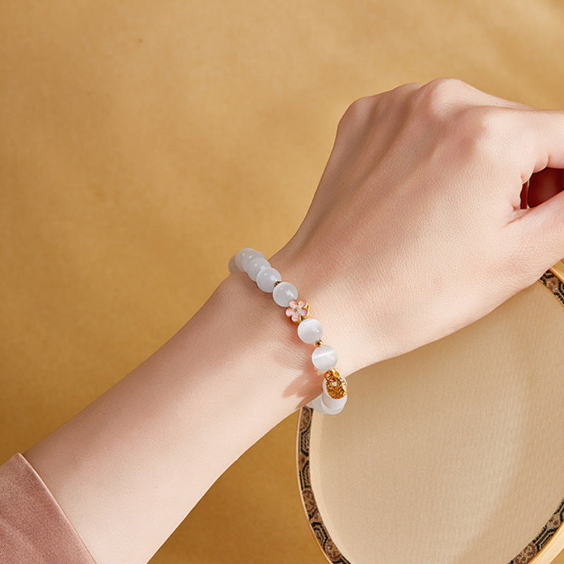 Original model wearing the peach blossom and blessing pouch bracelet beside a round fan