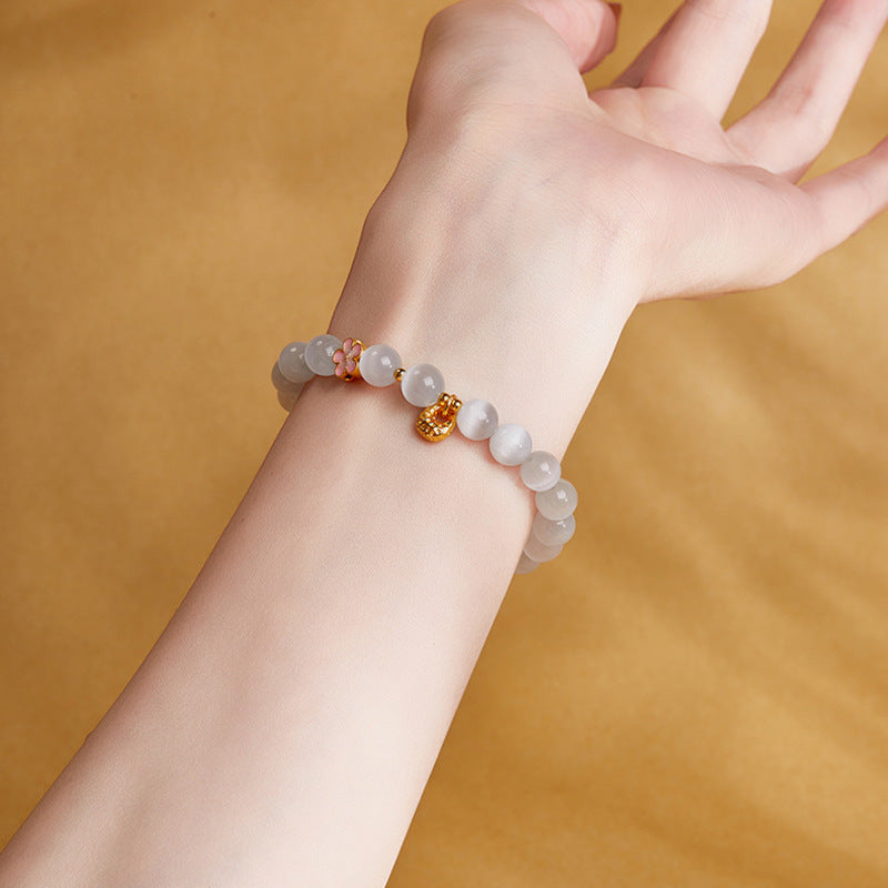 Original model wrist detail with pink enamel flower and gold-tone pouch