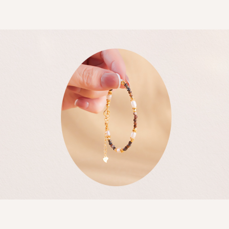 Hand holding adjustable six-pearl Pietersite bracelet