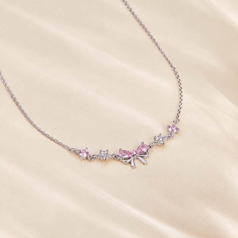 Pink bow necklace resting on cream satin