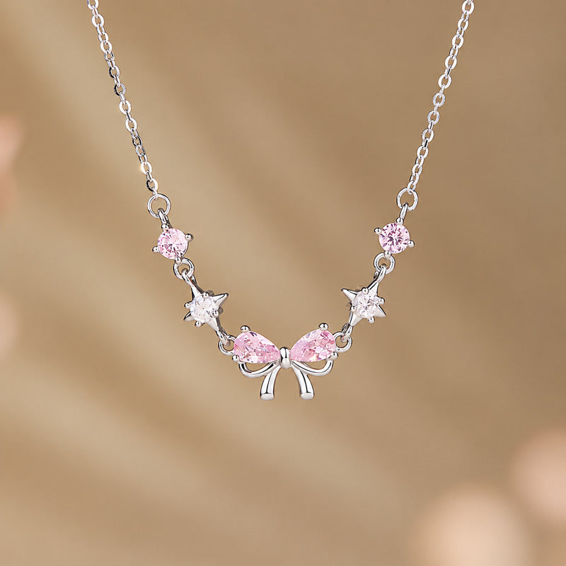 Pink bow and star necklace against a warm brown background