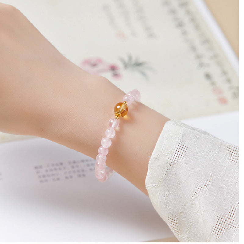 Pink crystal and citrine fortune bead bracelet worn on a wrist