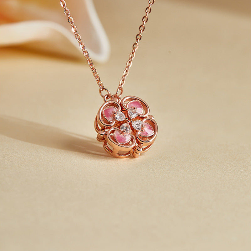 Pink enamel magnetic clover necklace on a warm fabric background