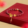 Pressed cinnabar four-leaf clover bracelet on a red fabric book, oblique view