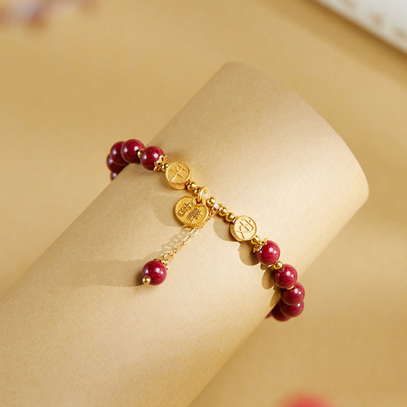 Pressed cinnabar bracelet and dangling charm on a gold-colored display