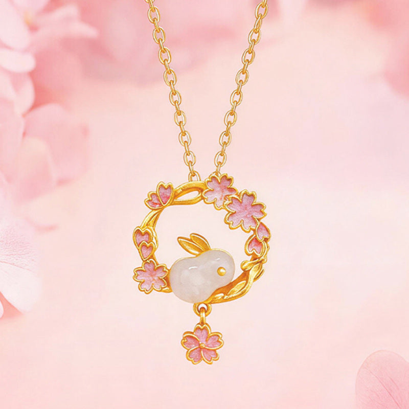Rabbit nephrite jade necklace displayed against soft pink blossoms