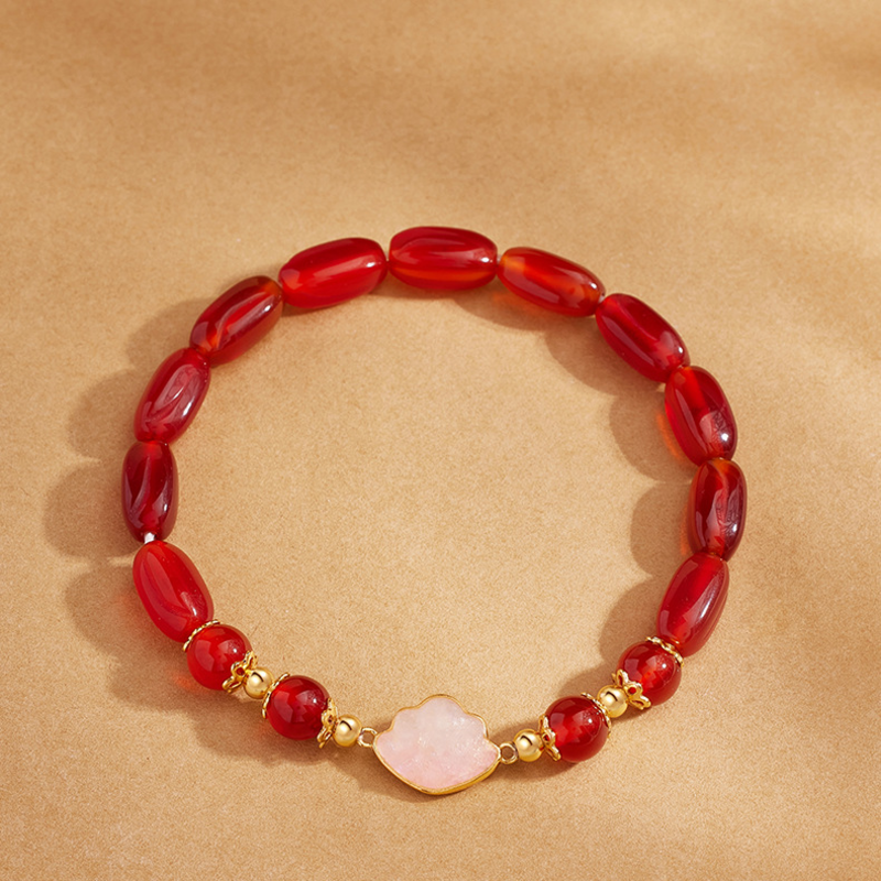 Top view of red agate cloud bracelet on gold background