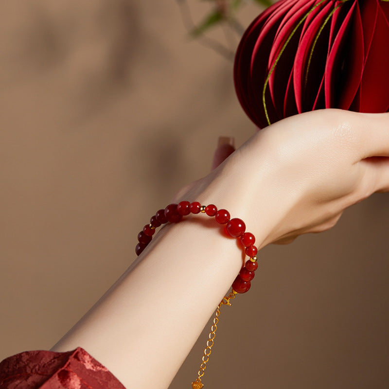 Red agate bracelet worn with extension chain hanging below wrist