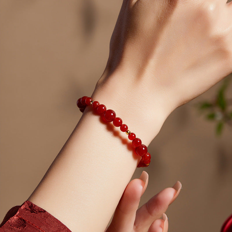 Red agate bracelet worn on wrist with burgundy sleeve