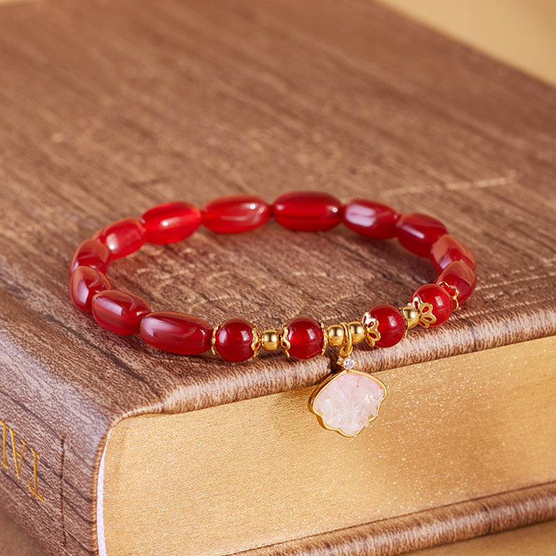Red agate shell charm bracelet displayed on book
