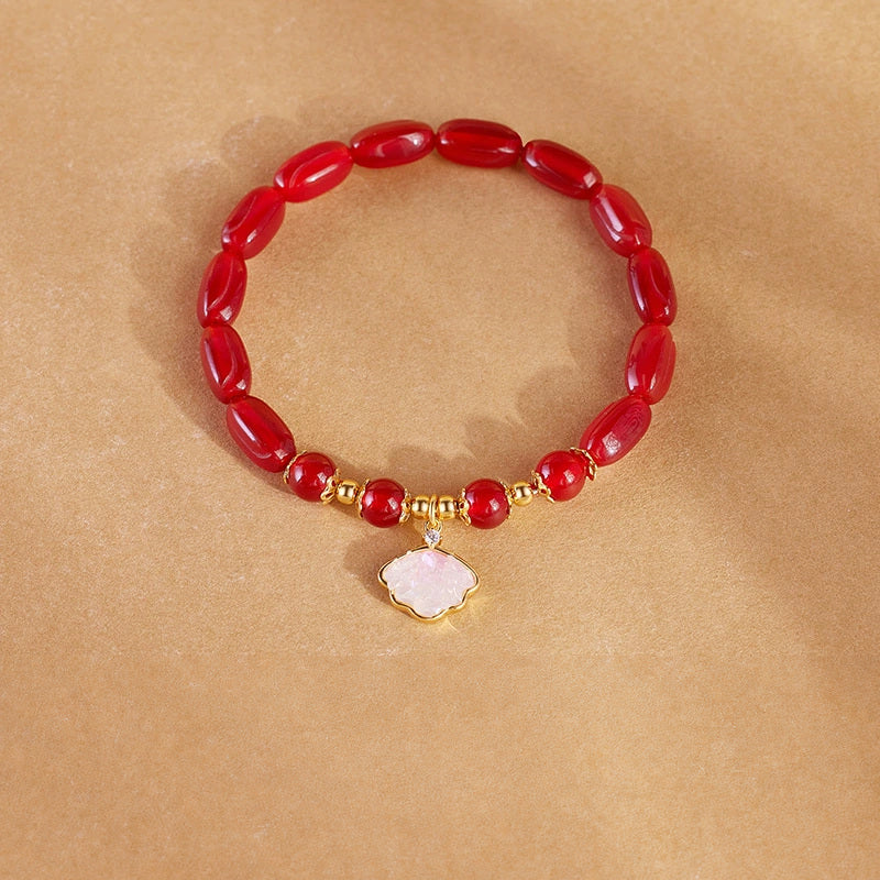 Red agate shell charm bracelet on warm tan background