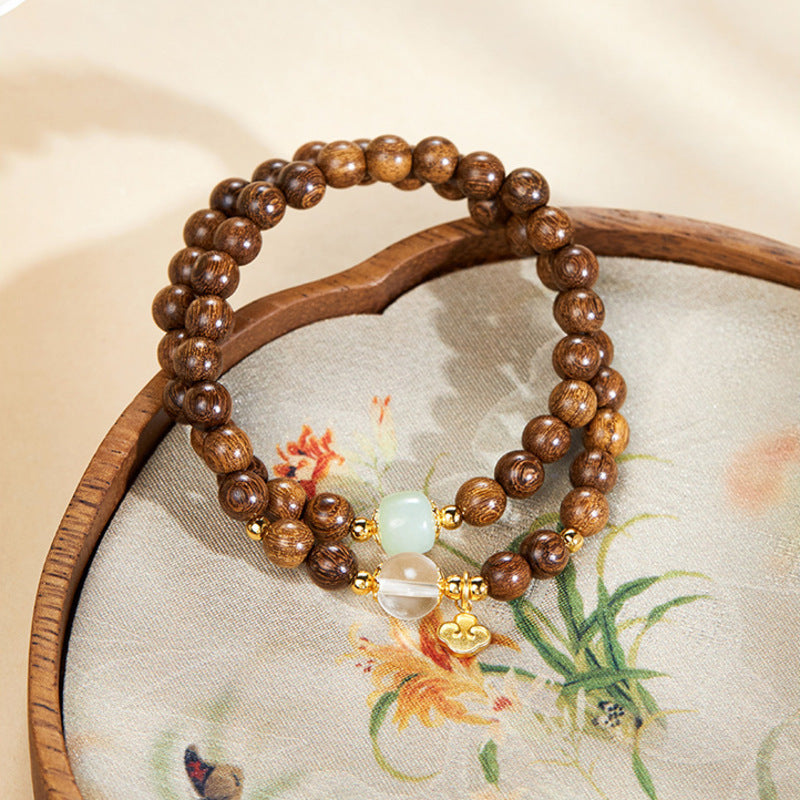 Double-wrap wood bracelet with nephrite jade and clear quartz on a patterned fan