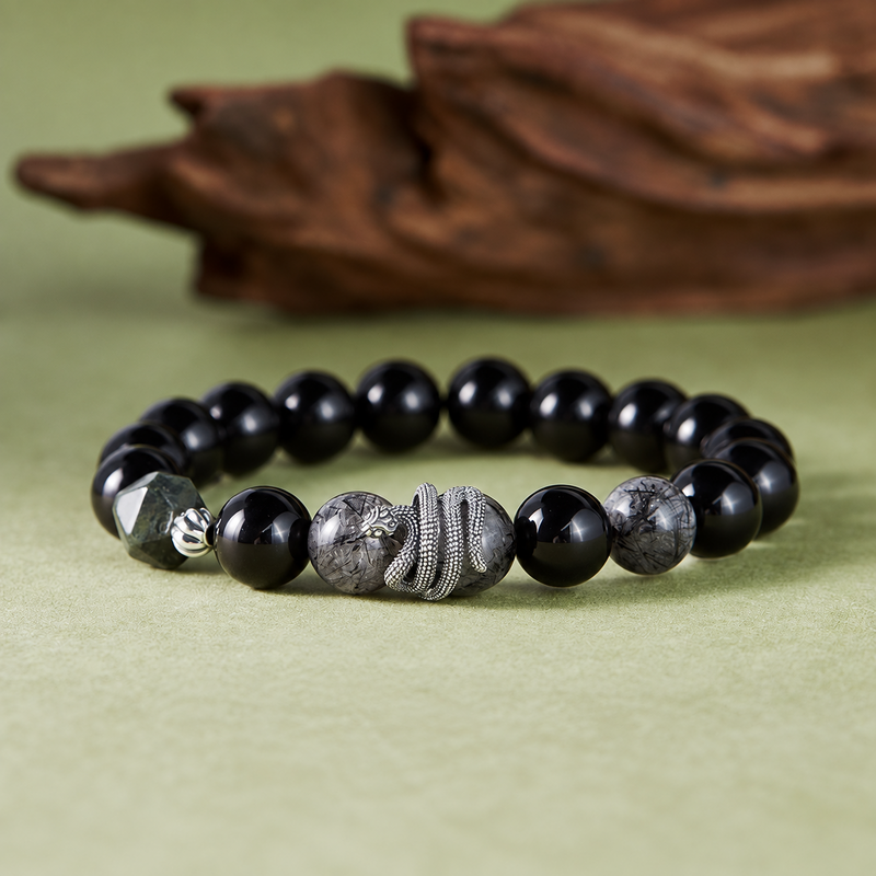 Obsidian and black rutilated quartz snake bracelet on a natural green background
