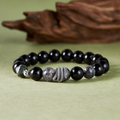 Obsidian and black rutilated quartz snake bracelet on a natural green background
