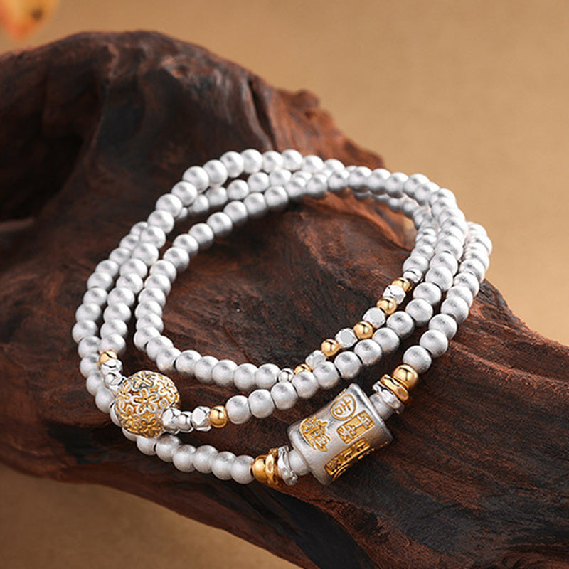 Blessing barrel and filigree ball silver bracelet detail on wood