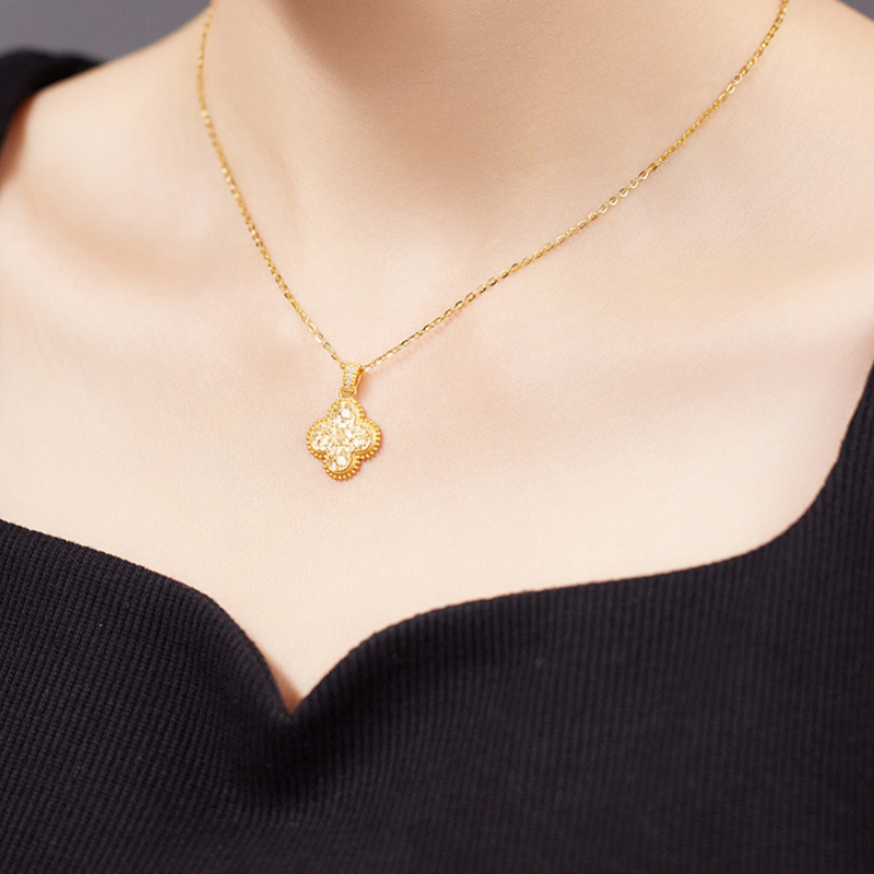 Woman wearing the gold-tone silver four-leaf clover necklace with a black neckline