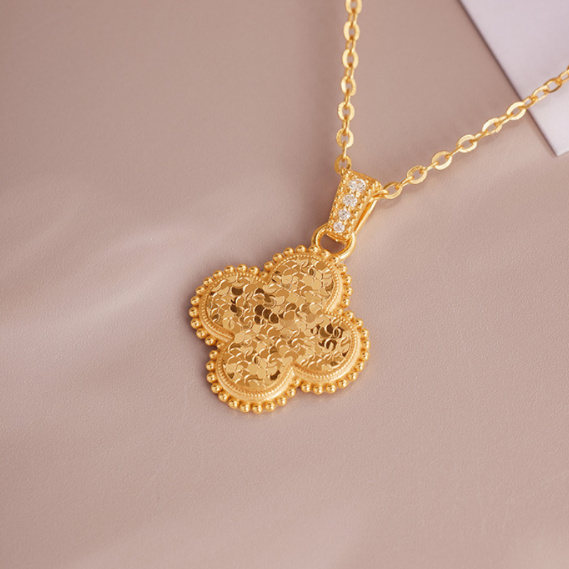 Close view of the gold-tone clover necklace on a taupe background