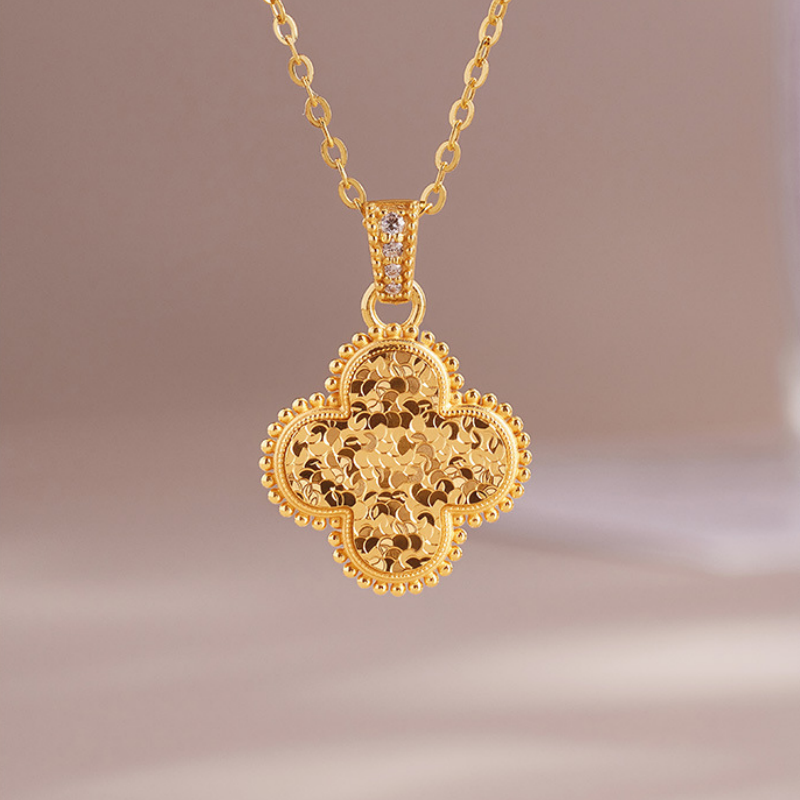 Gold-tone S925 silver four-leaf clover necklace suspended against a taupe background