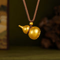 Gold-tone 999 fine silver gourd pendant on a braided cord against an olive background