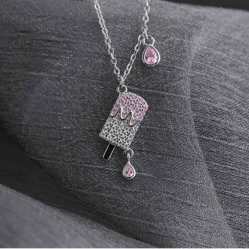 Silver popsicle necklace with pink and clear cubic zirconia on dark textured fabric