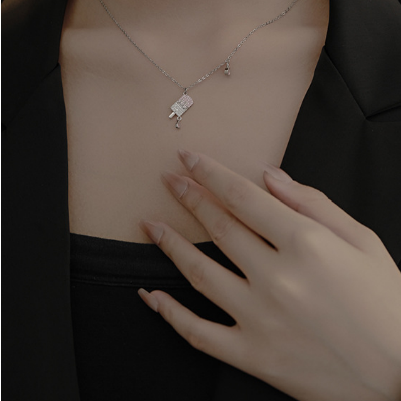 Original model wearing the silver popsicle necklace with her hand near the neckline