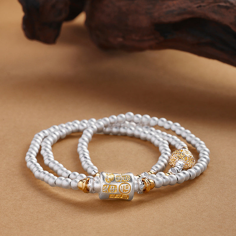 Fine silver triple wrap bracelet with filigree ball on sand