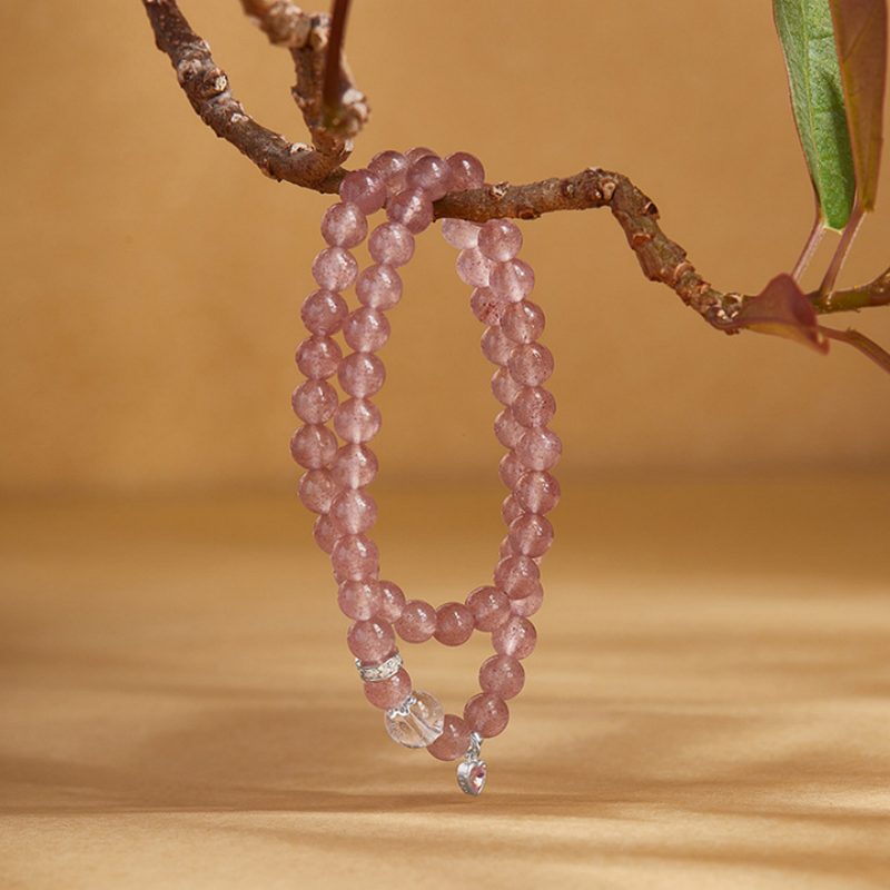 Pink crystal double wrap bracelet suspended from a branch with its heart charm visible