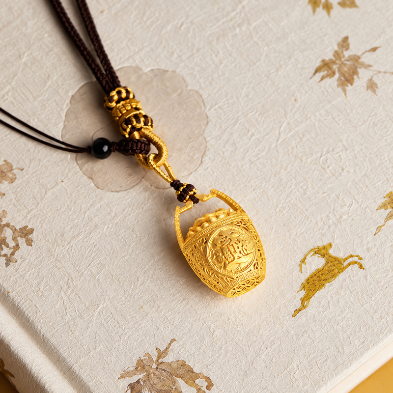 Oblique view of the gold-plated brass basket charm resting on a cream embroidered book