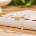 White chalcedony bamboo bracelet resting on a warm book background with Hetian jade tassel bead