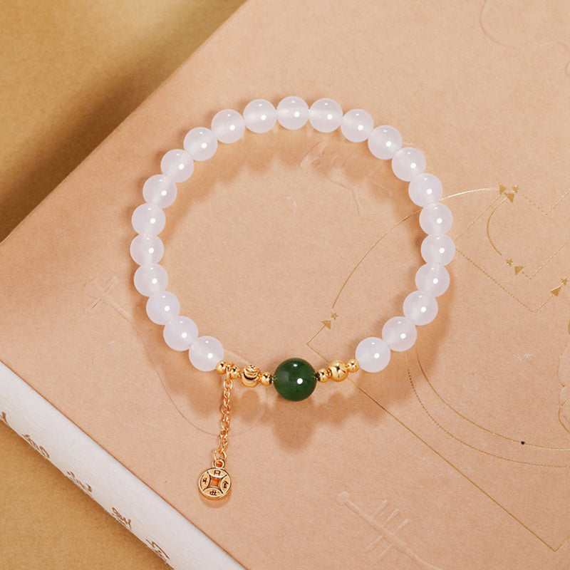 Overhead view of chalcedony jasper bracelet and dangling coin charm