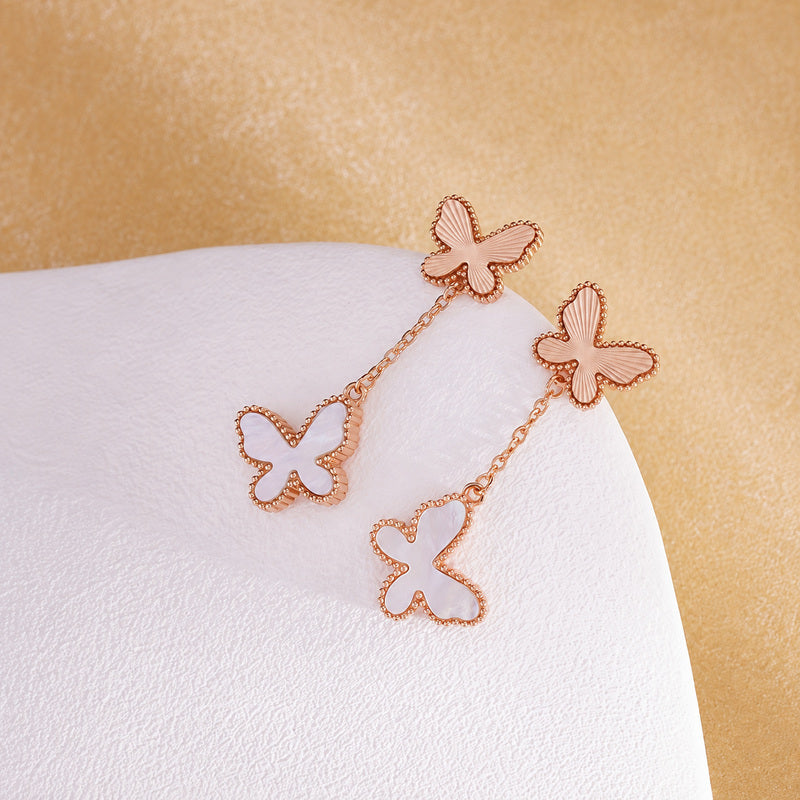 White mother-of-pearl butterfly earrings diagonal flat lay