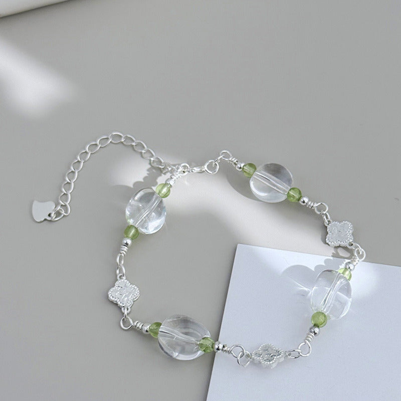 White quartz clover bracelet styled on a soft gray background