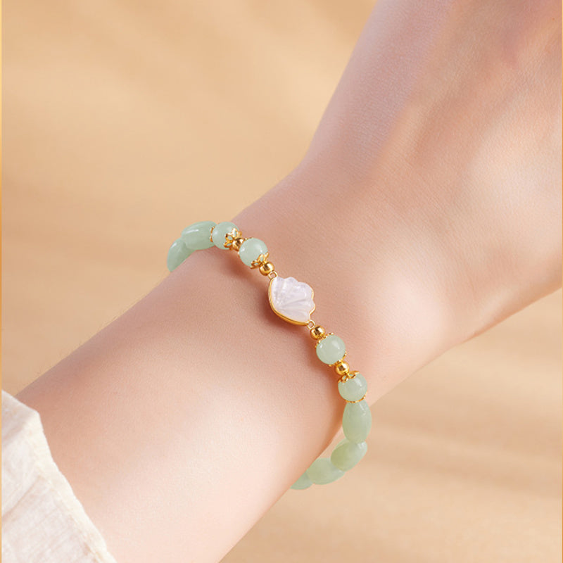 Nephrite jade bracelet with white shell fan worn on wrist