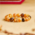 Yellow inclusion quartz and tiger's eye bracelet on a warm golden background