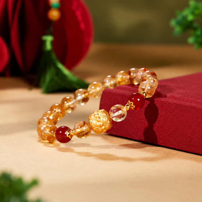Lotus bracelet resting against red fabric with translucent yellow quartz beads