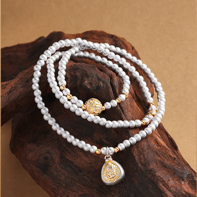 Sandblasted silver bead bracelet with deity charm on wood