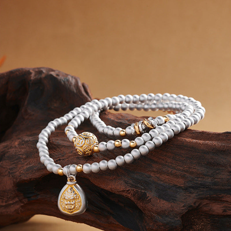 Triple-wrap silver deity bracelet displayed across dark wood