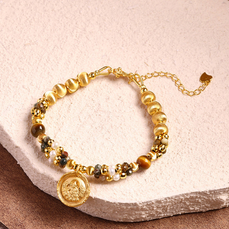 Yellow Wealth Deity pietersite pearl bracelet on a textured stone background