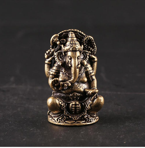 Front view of antique brass Ganesha statue displayed on a dark pedestal