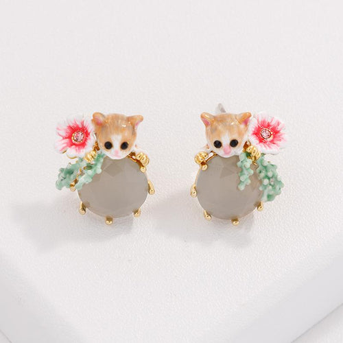 Floral cat rhinestone earrings displayed upright on a white block with gold-tone details