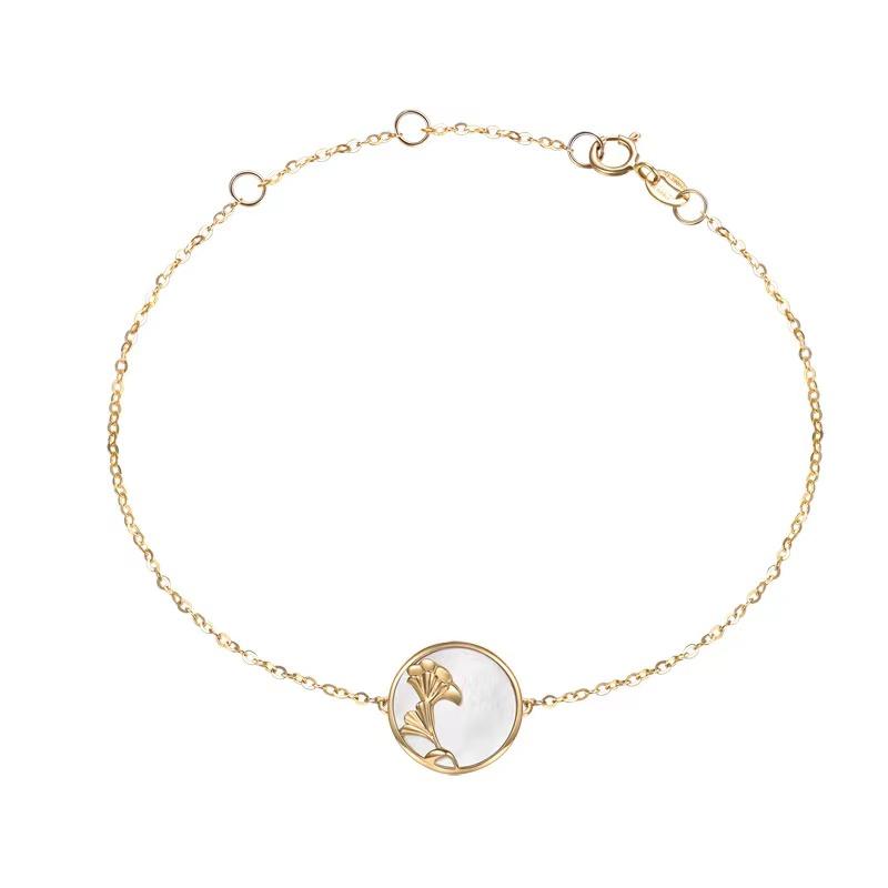 Delicate gold chain bracelet with round ginkgo leaf and pearl white charm on white
