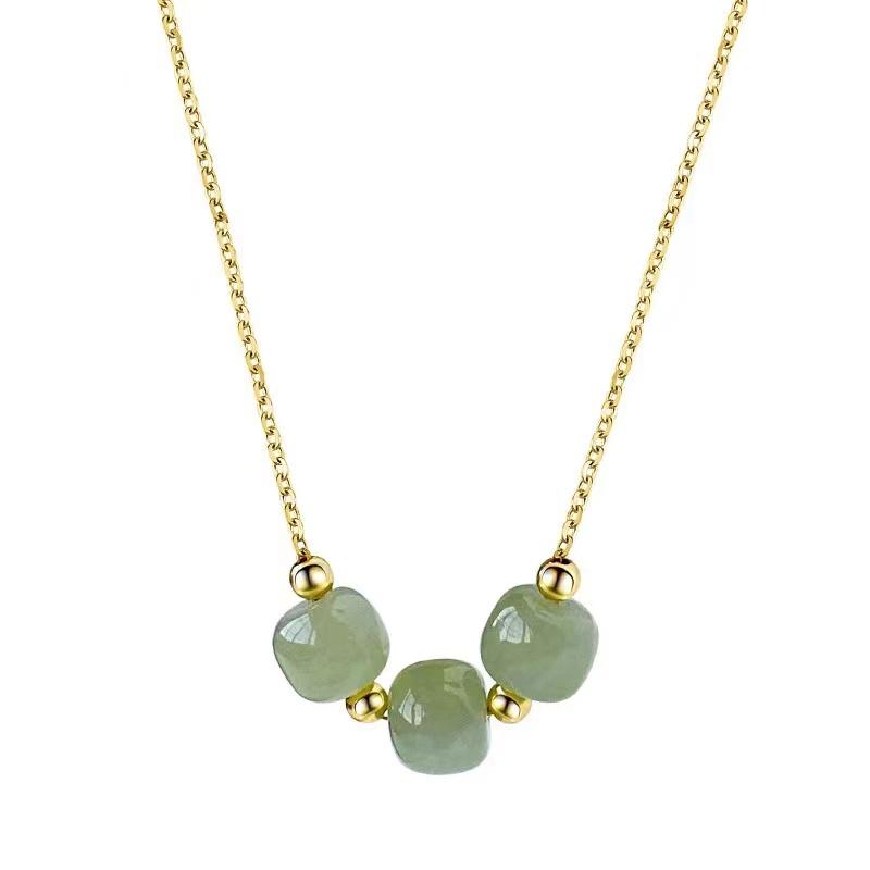 Pale green Hetian jade trio necklace with gold-tone chain displayed against a white background