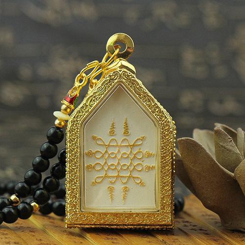 Back of house shaped gold Buddha amulet featuring a white panel with gold yantra design